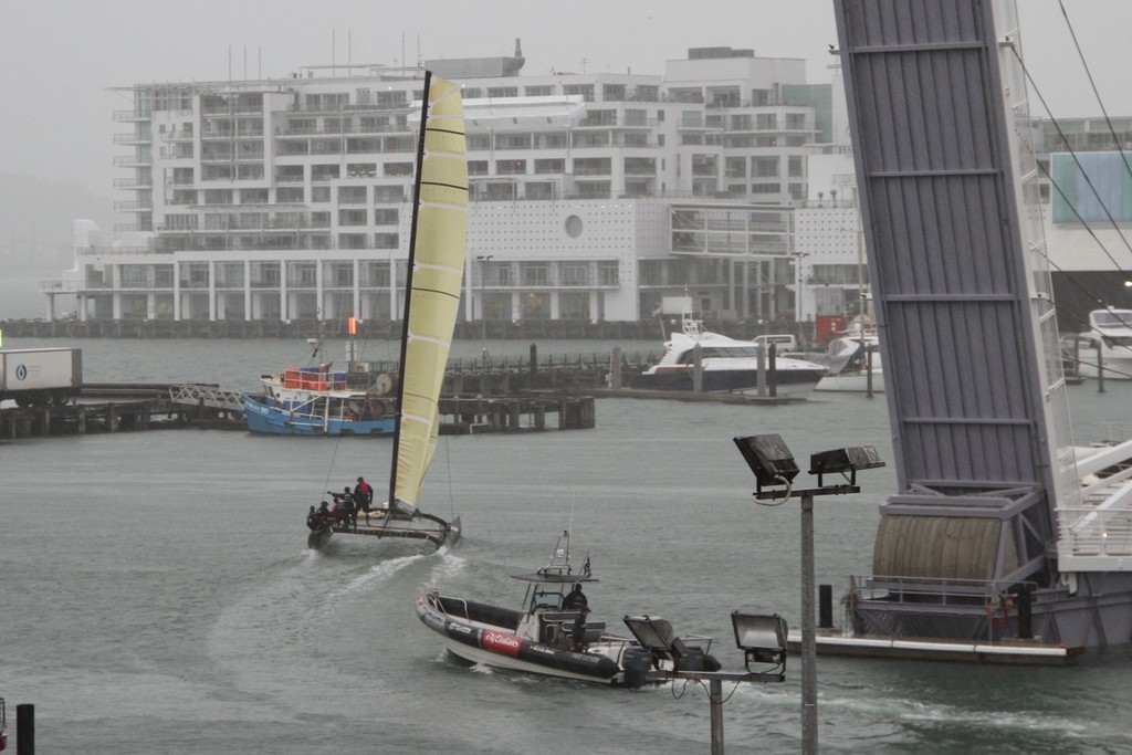 Emirates Team NZ’s SL-33 begins to fly a hull as she leaves the team’s base in the Viaduct harbour and heads off for a training session in the mid-winter murk. © Richard Gladwell www.photosport.co.nz